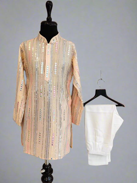 Beige embroidered shirt on a mannequin and white pants on a hanger against a gray background