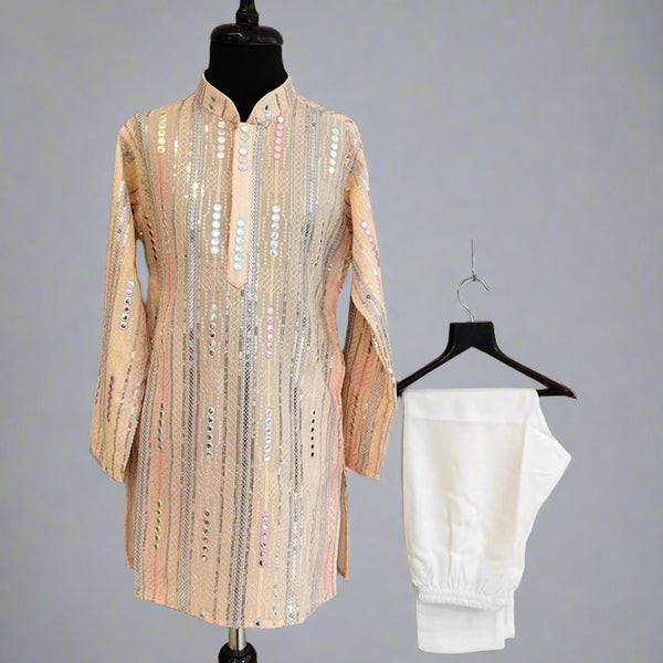 Beige embroidered shirt on a mannequin and white pants on a hanger against a gray background