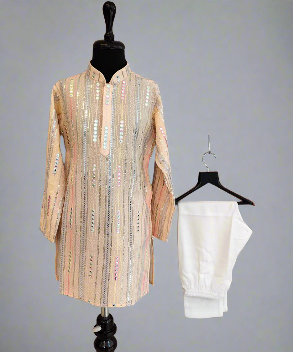 Beige embroidered shirt on a mannequin and white pants on a hanger against a gray background