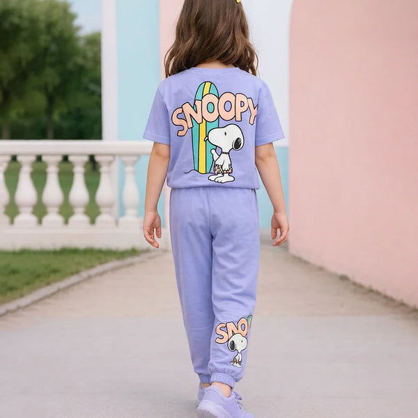Child wearing a purple Snoopy-themed outfit walking on a path with a scenic background.