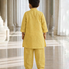 Child wearing a yellow traditional outfit standing in a large, open, and architecturally significant building.