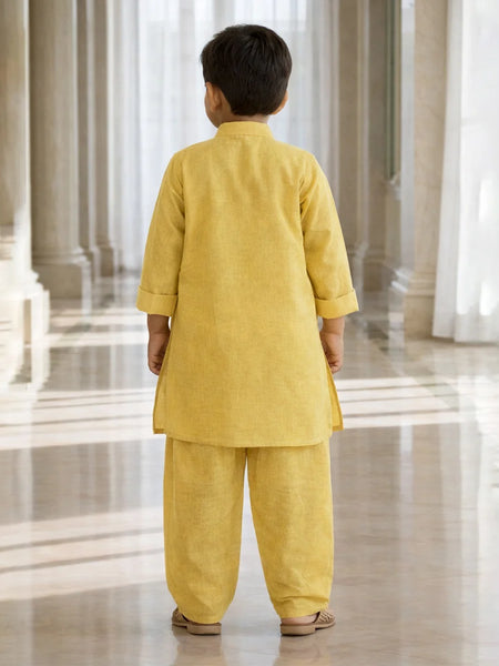 Child wearing a yellow traditional outfit standing in a large, open, and architecturally significant building.