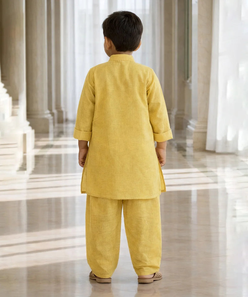 Child wearing a yellow traditional outfit standing in a large, open, and architecturally significant building.