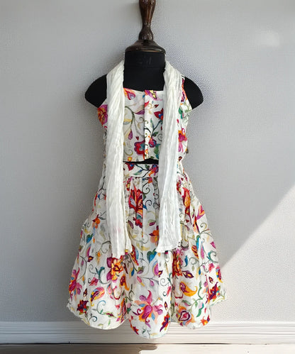 Floral dress with a white scarf on a mannequin against a plain background