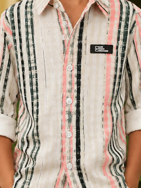 A close-up of a man wearing a textured, long-sleeve button-up shirt with vertical stripes in black, pink, and white. The shirt features a black brand patch on the left chest that reads 'THE CHOICE BRAND'.