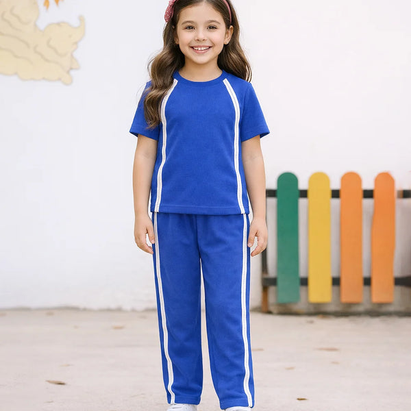 Young girl wearing a blue tracksuit with white stripes in an outdoor setting.