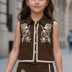 Young girl wearing a brown outfit with white embroidery in an urban setting