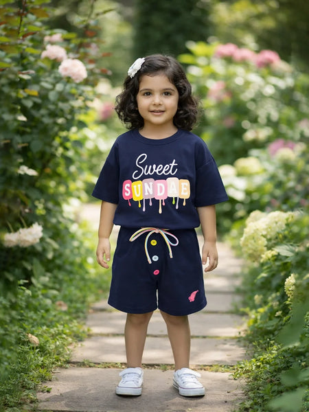 Child wearing a navy blue outfit with colorful text standing in a garden.