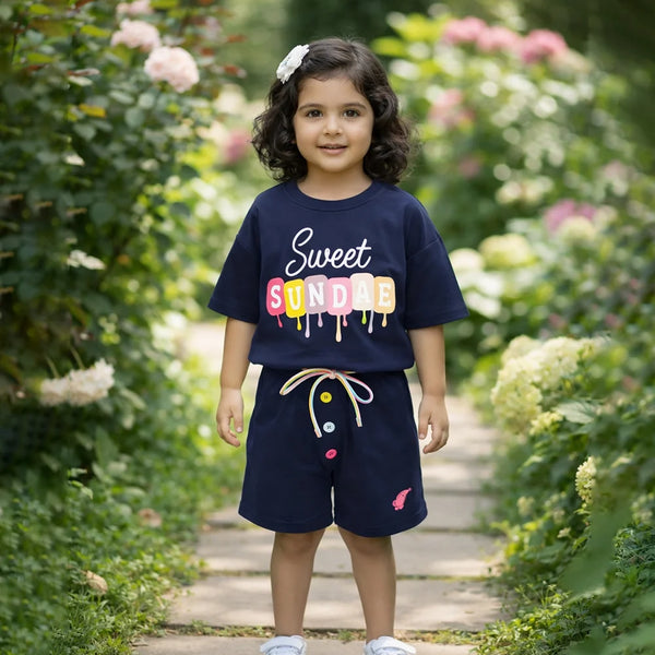 Child wearing a navy blue outfit with colorful text standing in a garden.