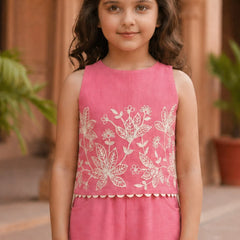 Young girl wearing a pink sleeveless top with white floral embroidery in an outdoor setting.