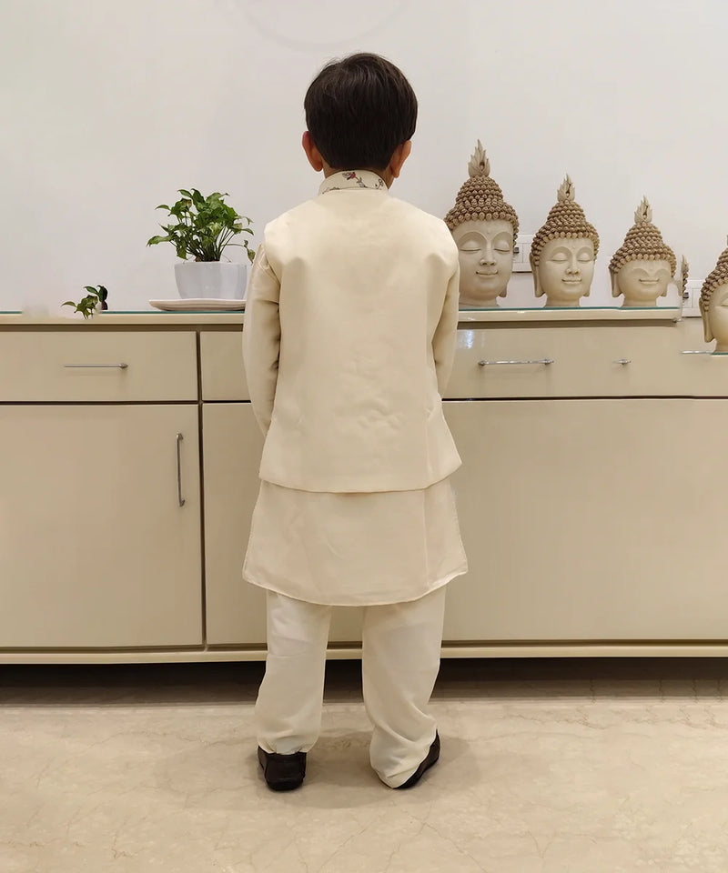 It is a back view of the boy wearing a cream colour kurta pyjama. The back of the jacket is plain.