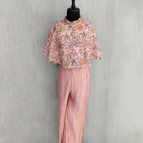 Mannequin wearing a pink floral top and pleated pants against a gray background