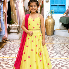 Young girl in a yellow dress with red heart patterns standing in a store.