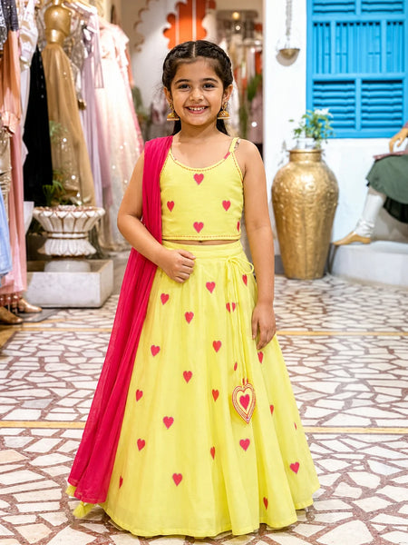 Young girl in a yellow dress with red heart patterns standing in a store.