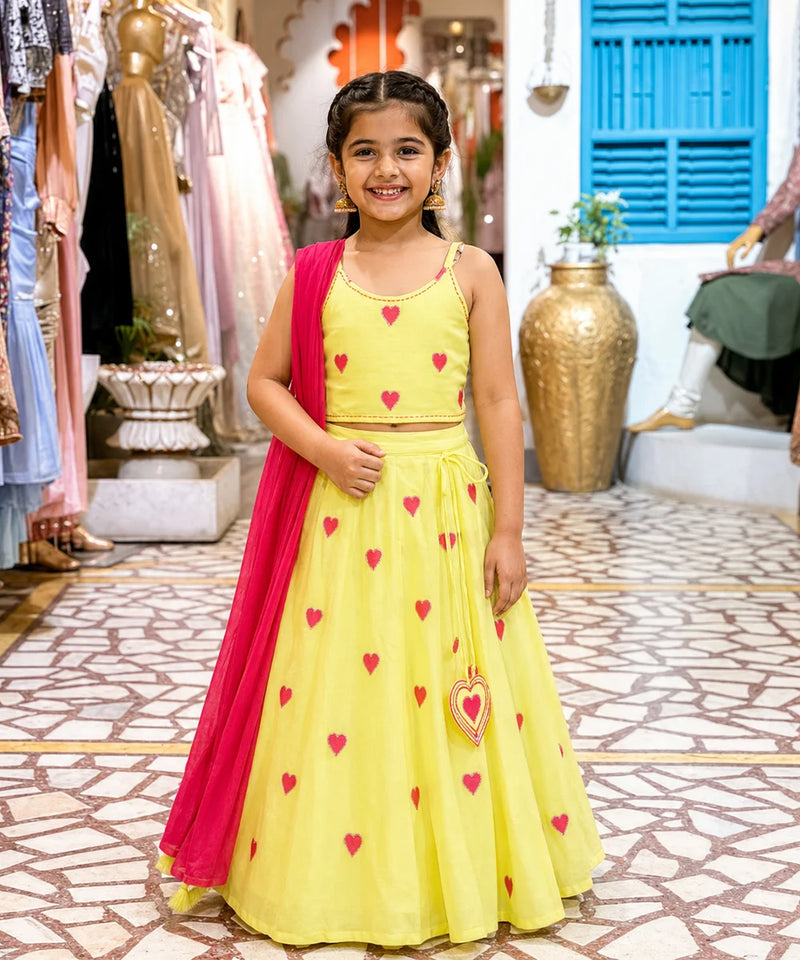 Young girl in a yellow dress with red heart patterns standing in a store.