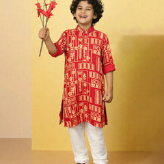 Child wearing a red patterned kurta with white pants, holding red flowers against a yellow background