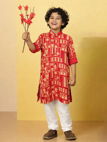Child wearing a red patterned kurta with white pants, holding red flowers against a yellow background