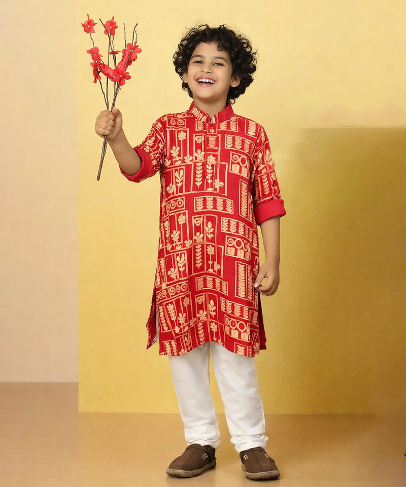 Child wearing a red patterned kurta with white pants, holding red flowers against a yellow background