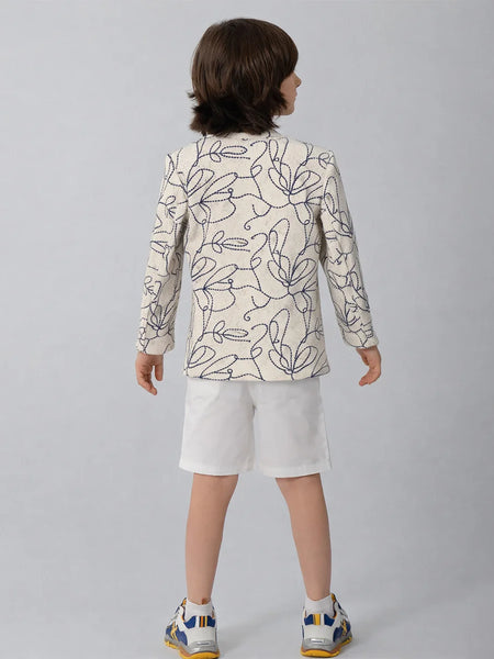 Child wearing a patterned blazer and white shorts on a plain background