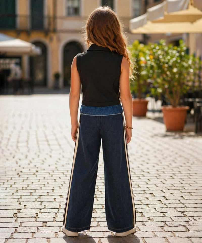 Woman wearing a black sleeveless top and blue wide-leg pants on a cobblestone street.