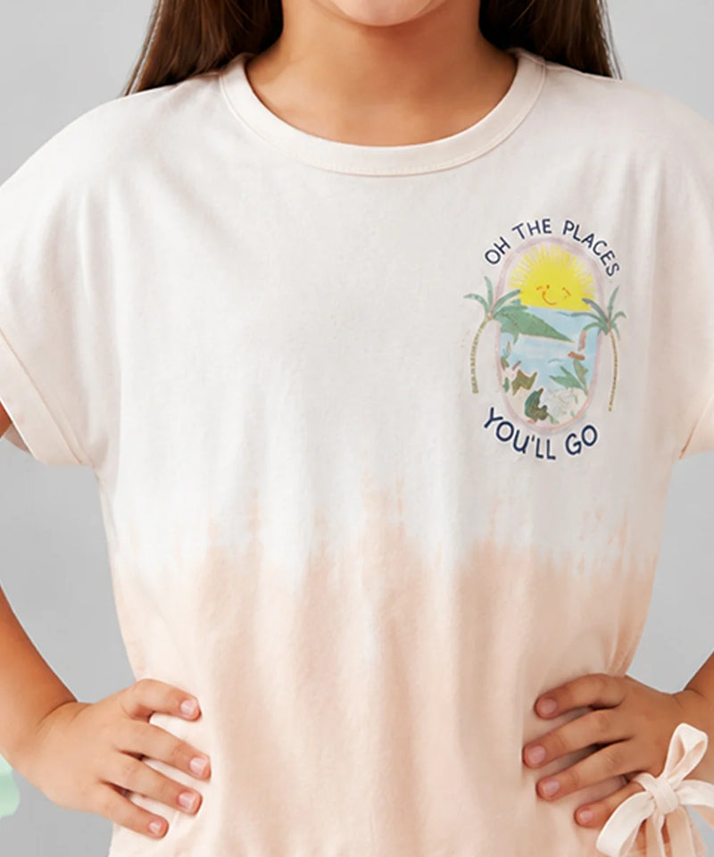 A close-up of a person wearing a short-sleeve crew-neck T-shirt. The shirt is off-white at the top and fades into a very light peach-pink at the bottom, with a colorful beach graphic and the text 'ON THE PLACES YOU'LL GO' printed on the left chest.