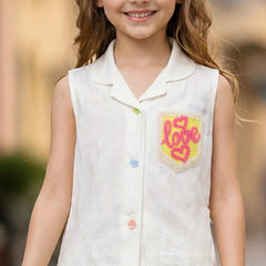 Young girl wearing a white sleeveless shirt with a colorful 'LOVE' design on a blurred outdoor background
