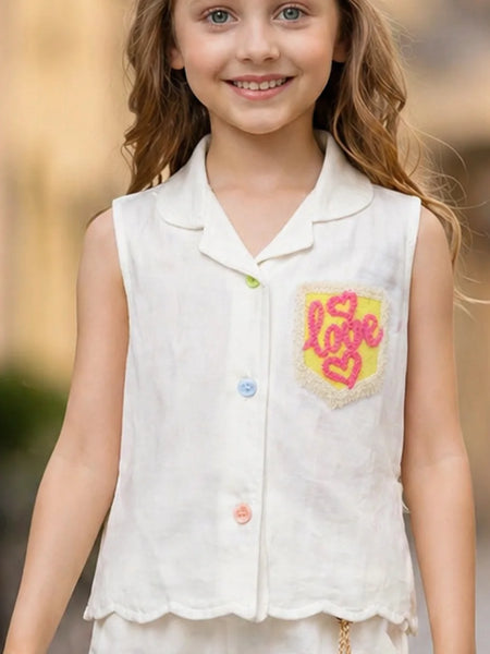 Young girl wearing a white sleeveless shirt with a colorful 'LOVE' design on a blurred outdoor background