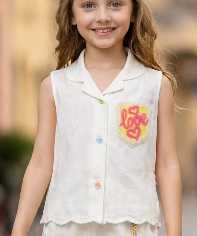 Young girl wearing a white sleeveless shirt with a colorful 'LOVE' design on a blurred outdoor background