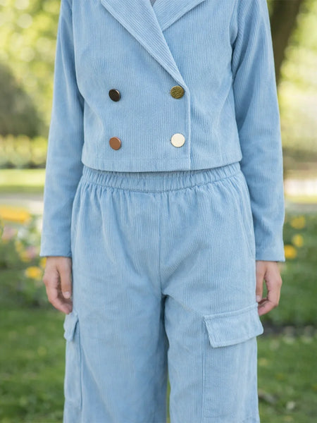 Light blue corduroy outfit with buttons in a park setting