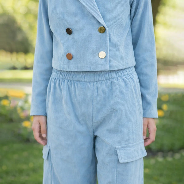 Light blue corduroy outfit with buttons in a park setting