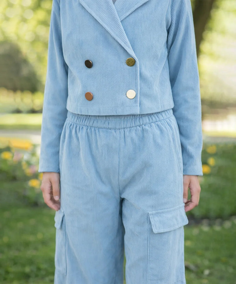 Light blue corduroy outfit with buttons in a park setting