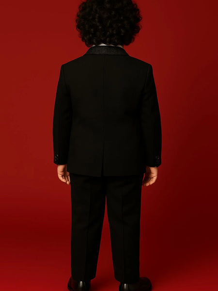 Person wearing a black suit standing against a red background