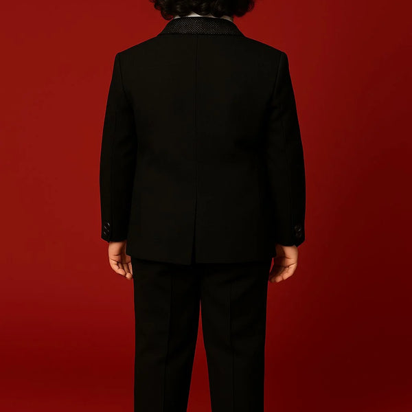 Person wearing a black suit standing against a red background