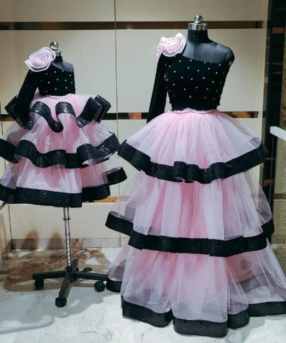 It’s a black and pink Colored one-shoulder ruffle gown for mother daughter with a big floral and pearl detailing. 