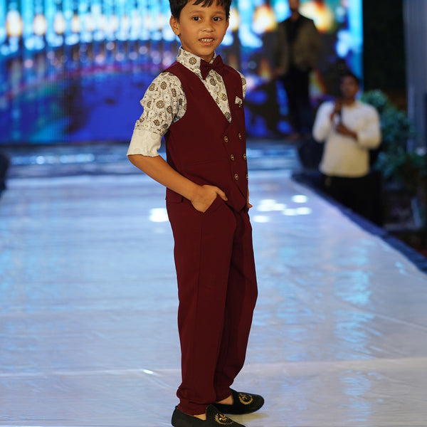 This wedding dress for small boy consists of a maroon Colored waistcoat, matching pants and a self-printed white Coloured shirt. It features a matching bow, a cute broach and a printed pocket square.