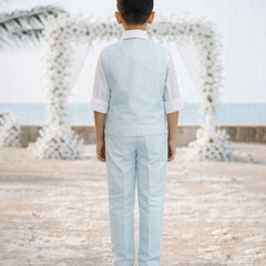 Child in a light blue suit standing in front of decorative white arches.