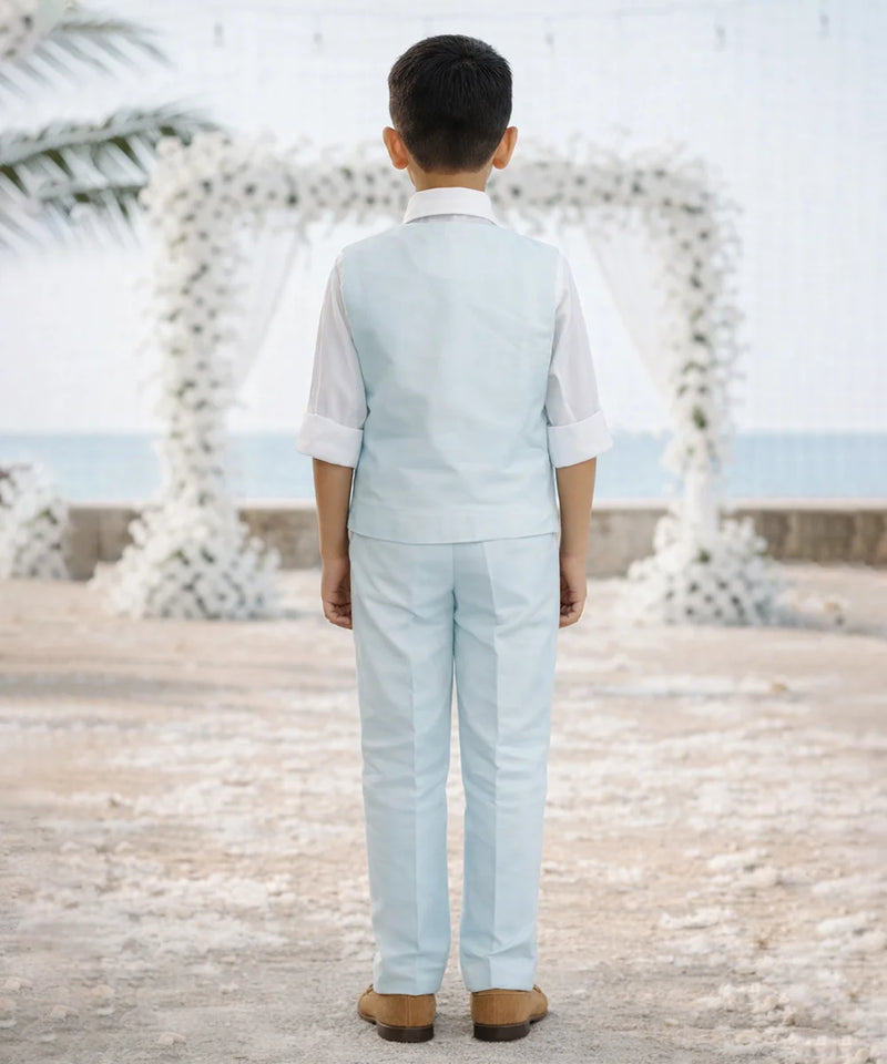 Child in a light blue suit standing in front of decorative white arches.