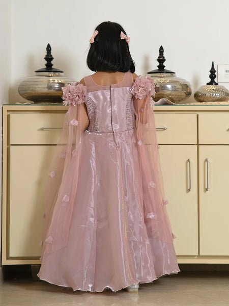Child wearing a pink floral dress standing in front of a beige cabinet.