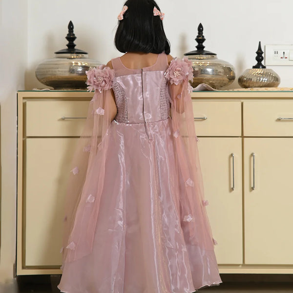 Child wearing a pink floral dress standing in front of a beige cabinet.