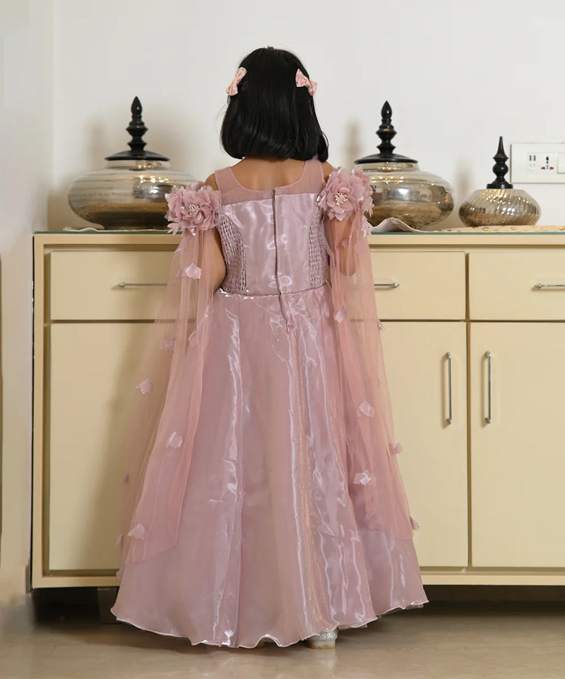 Child wearing a pink floral dress standing in front of a beige cabinet.