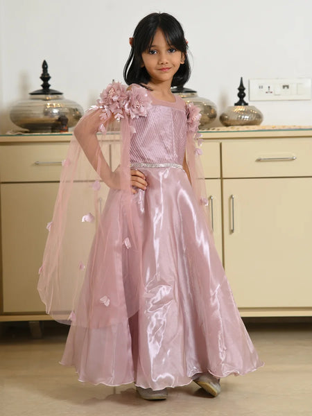 Young girl in a pink dress with floral details standing in a room.