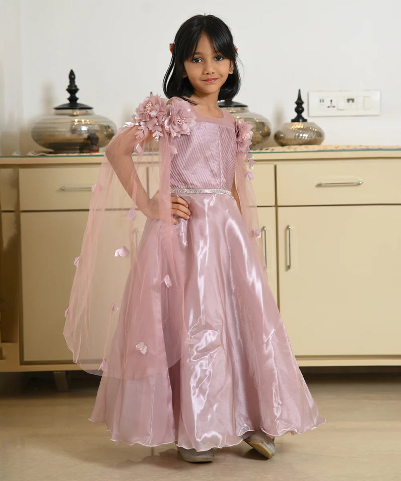 Young girl in a pink dress with floral details standing in a room.