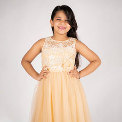 Young girl wearing a beige dress with lace top against a white background