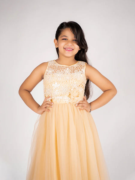 Young girl wearing a beige dress with lace top against a white background