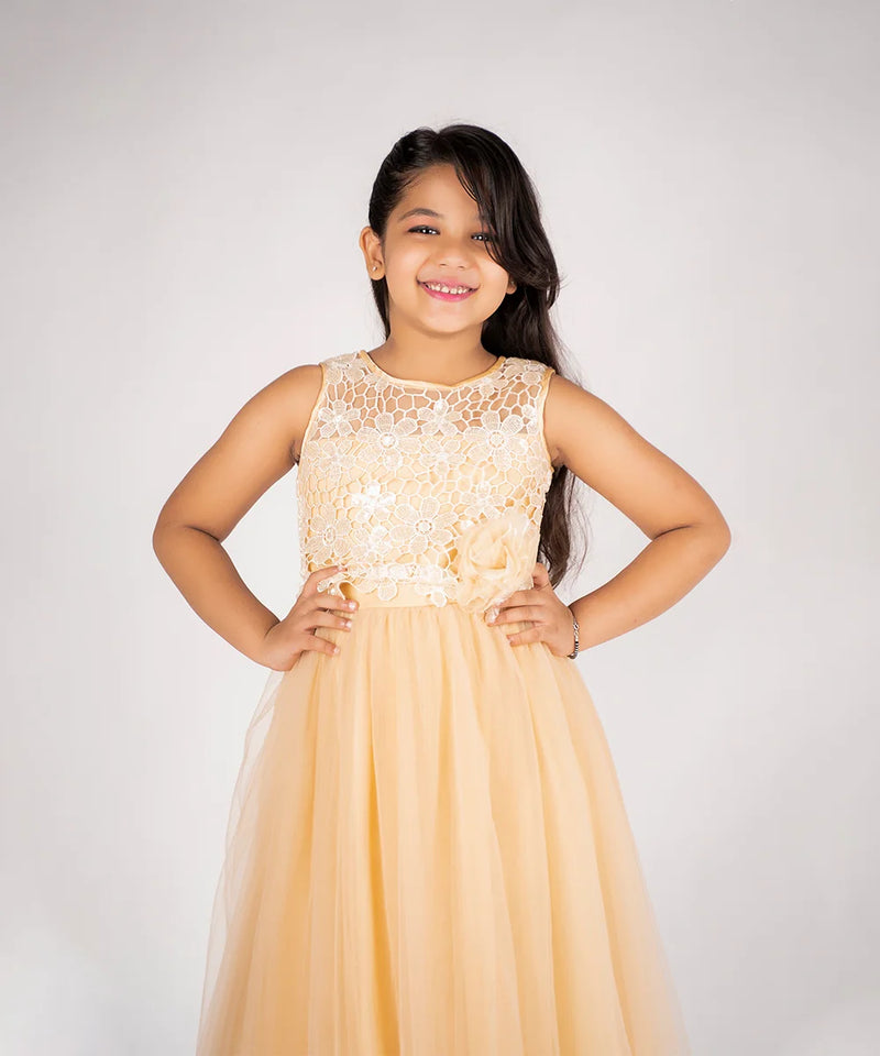 Young girl wearing a beige dress with lace top against a white background