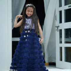 Young girl in a blue dress standing in a doorway.