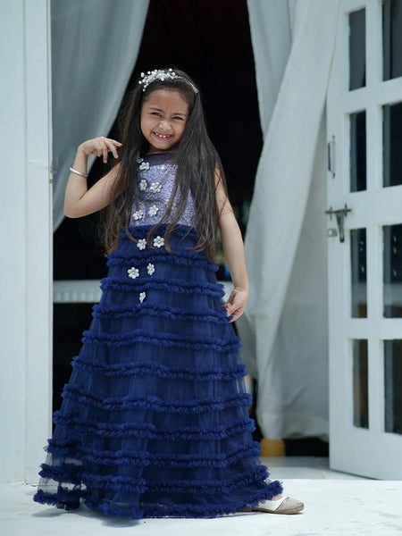 Young girl in a blue dress standing in a doorway.