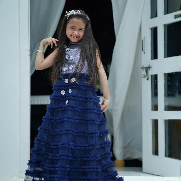Young girl in a blue dress standing in a doorway.