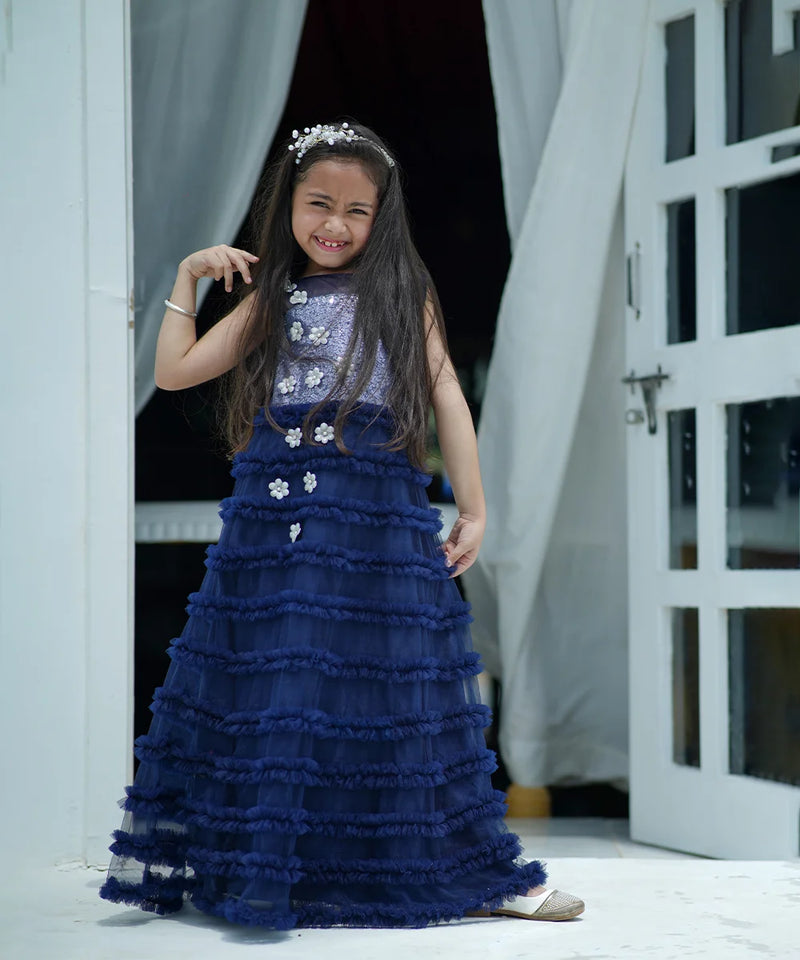 Young girl in a blue dress standing in a doorway.