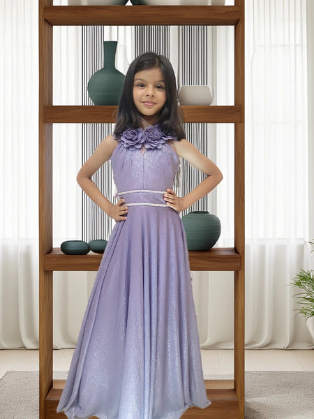 Young girl in a purple dress standing in front of a wooden shelf with decorative vases.